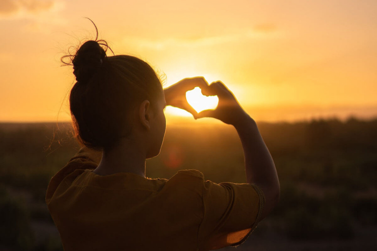 Woman Sitting while Showing Heart Sign Hands