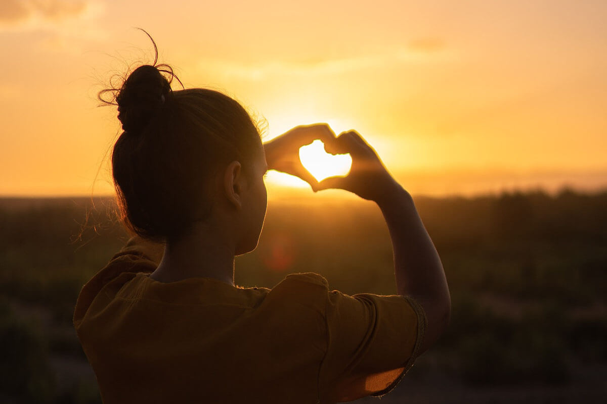 Woman Sitting while Showing Heart Sign Hands